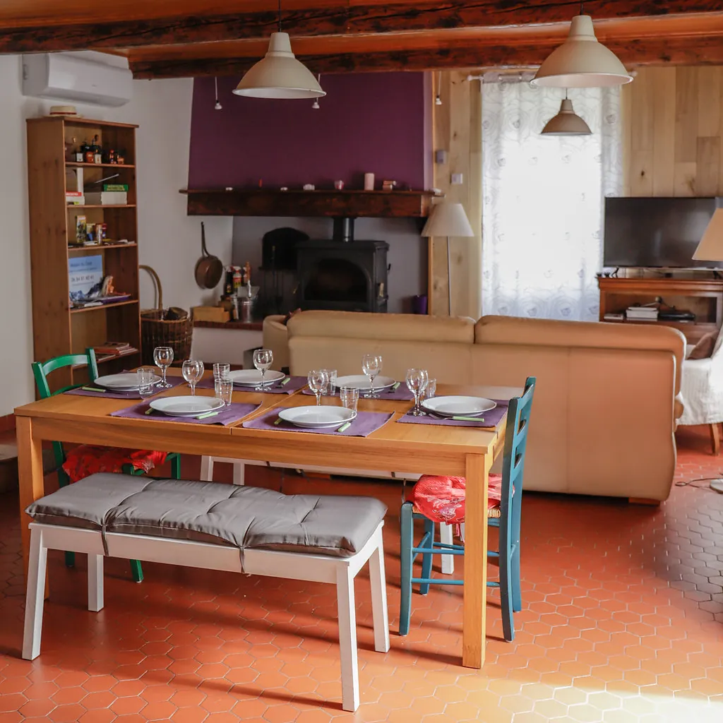 La pièce de vie : cuisine, grande table et salon autour du poêle